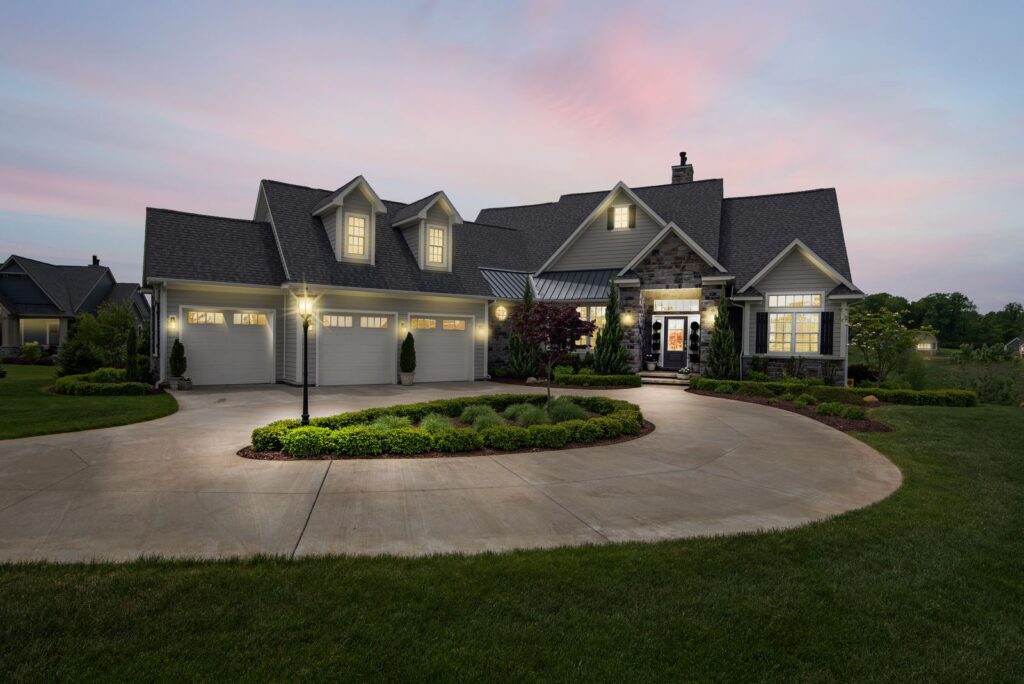 Custom-built suburban home illuminated at dusk with exterior lighting and landscaping