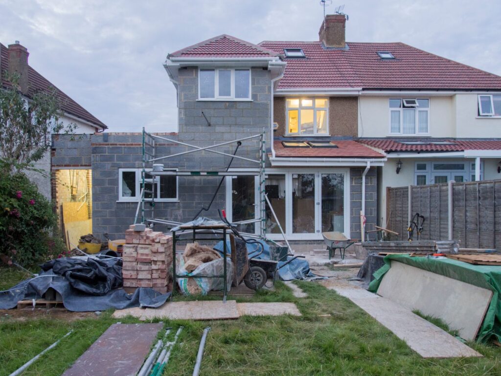 Suburban Westchester NY home undergoing a second-story addition with scaffolding and building materials