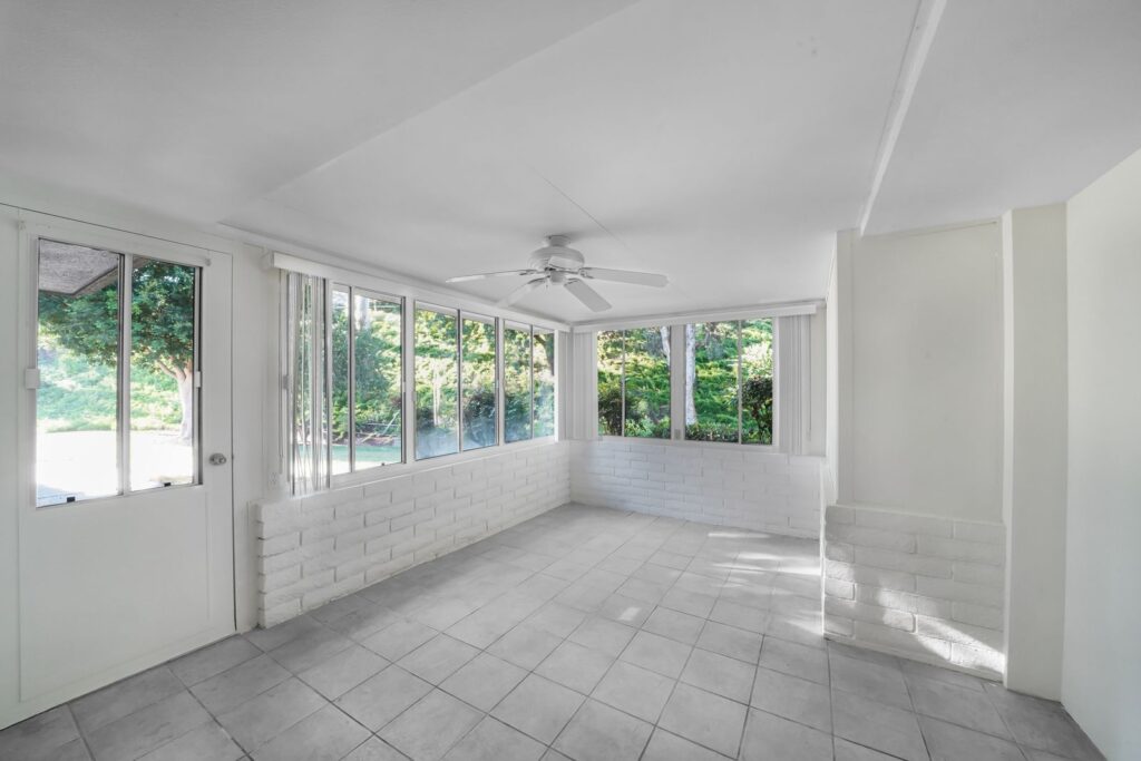 Finished sunroom addition with tiled floor, large windows, and ceiling fan on a Westchester NY home
