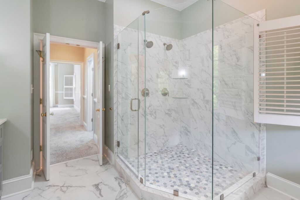 Spacious luxury bathroom remodel with contemporary marble shower and frameless glass doors