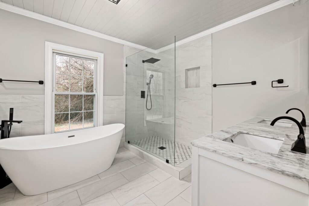 Sleek luxury bathroom remodel with freestanding tub, frameless glass shower, and marble accents