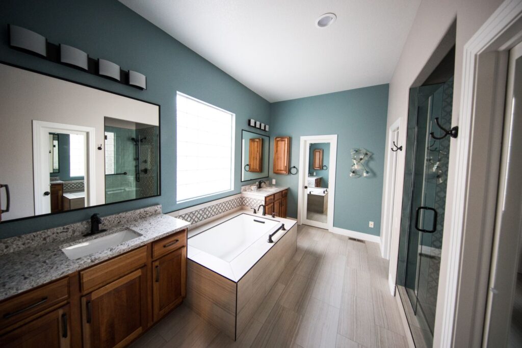 Spacious luxury bathroom remodel with freestanding bathtub, wood cabinetry, and granite countertops