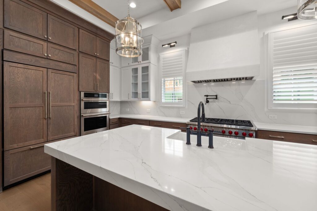 Luxury kitchen remodel with dark wood cabinetry, waterfall marble island, and pendant lighting