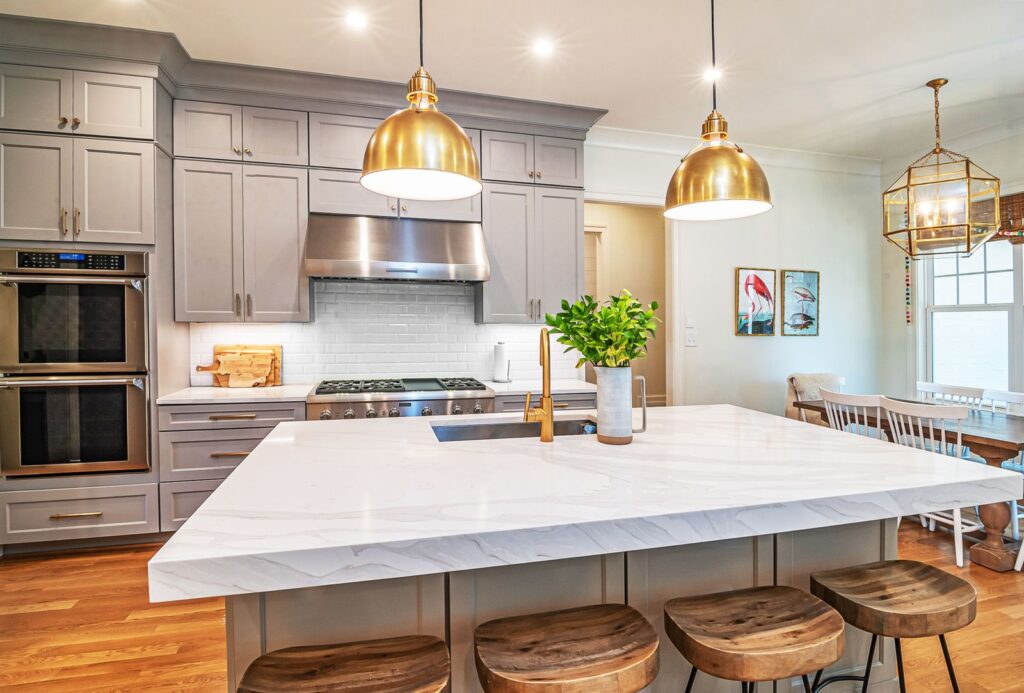 Gray shaker cabinetry kitchen remodel with marble island and brass dome pendant lights
