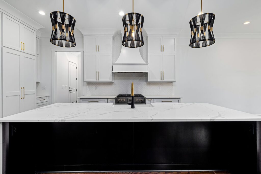 White shaker kitchen remodel with black waterfall island, quartz counter, and statement pendant lighting