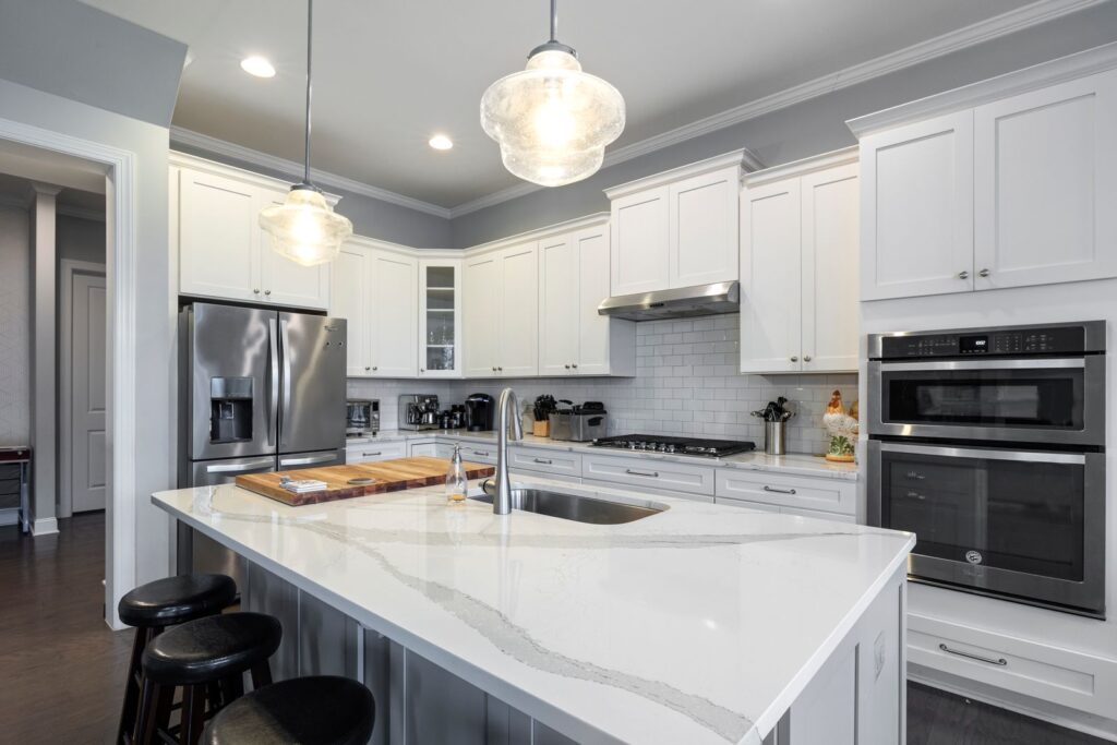 White shaker cabinetry kitchen remodel with quartz waterfall island and glass pendant lights