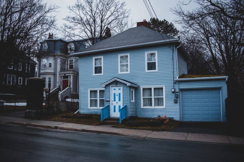 Residential home with light blue siding panels, white trim, and garage in Westchester NY